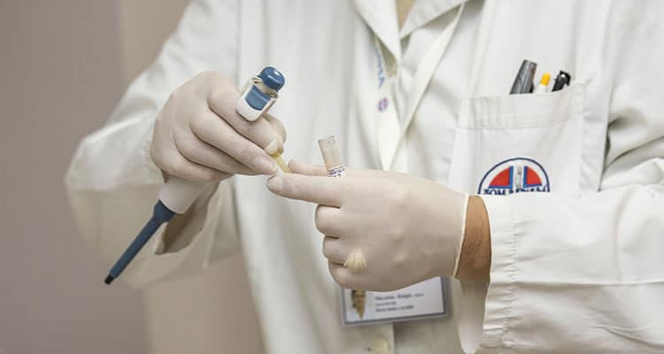 Médico de jaleco usando luvas e manuseando equipamentos